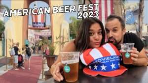 Due visitatori con birre durante l'American Beer Fest 2023 a Movieland, evento annuale di settembre con tema americano, indossano cappellini promozionali del parco a tema Hollywood