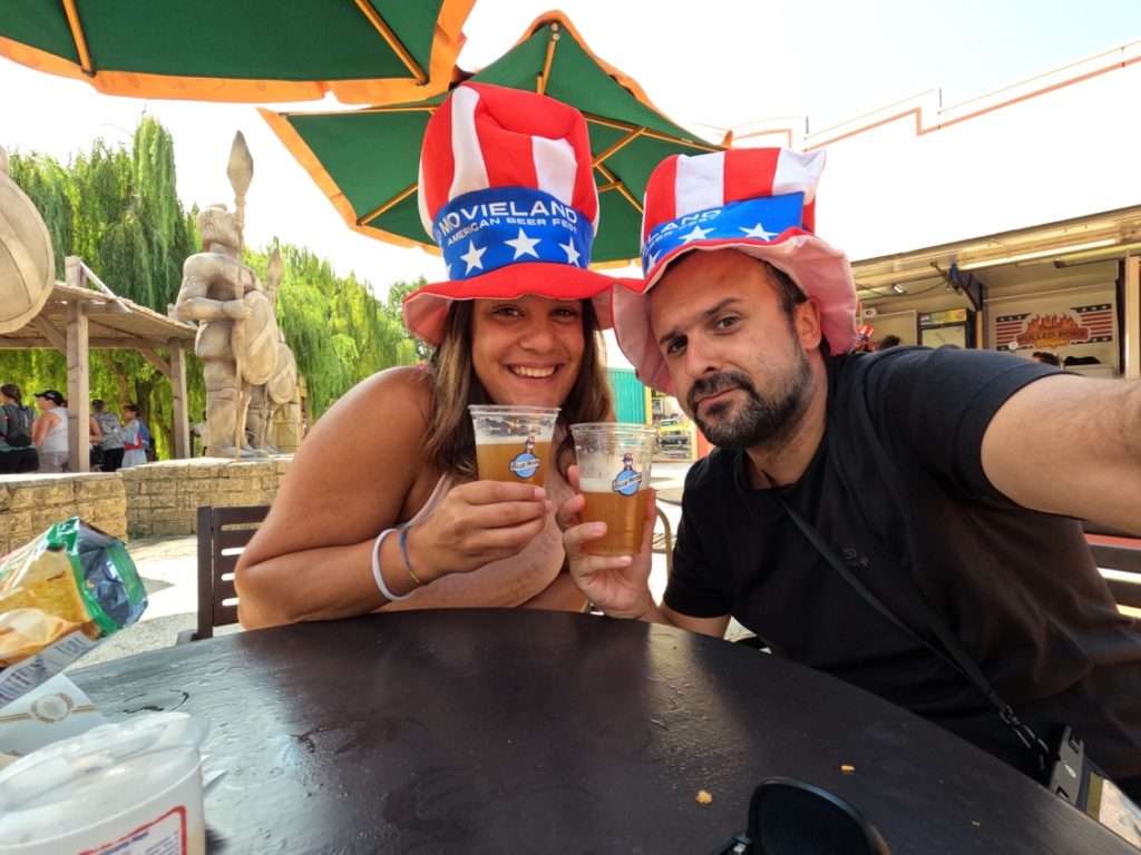 Foto ricordo di una coppia a Movieland con le birre in mano e il cappello americano