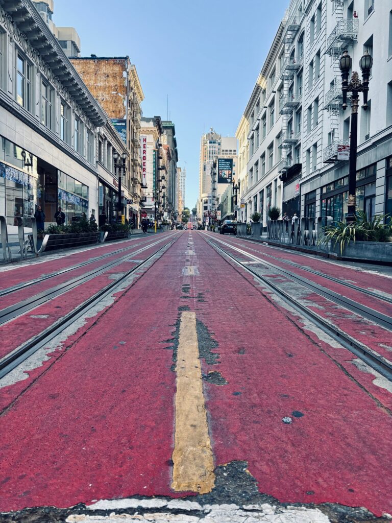 Market Street a San Francisco con superficie rosso rosa e binari del F-Line streetcar con edifici del downtown sullo sfondo