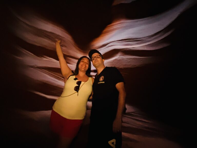Alessia in giallo e Michael di Red Lace dentro Antelope Canyon illuminati dalla luce naturale con pareti di arenaria arancioni, rosa e brune stratificate