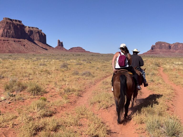 Due cavalieri a cavallo in Monument Valley con buttes rossi sullo sfondo