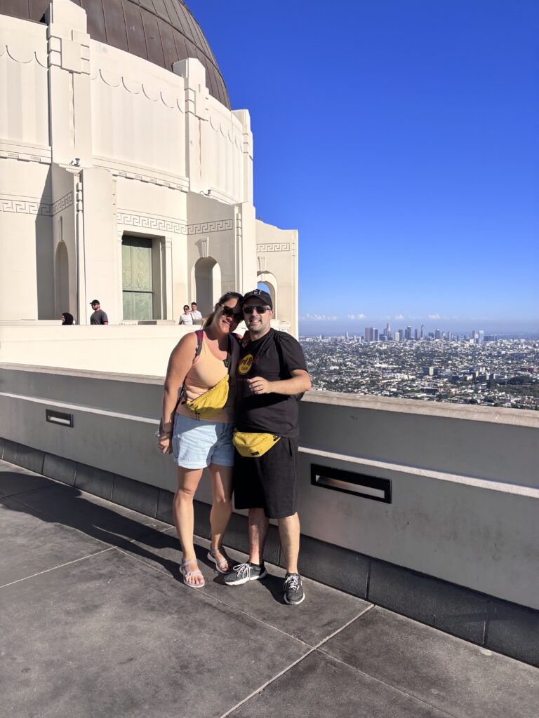 Alessia e Michael abbracciati sulla terrazza del Griffith Observatory con vista dello skyline di Los Angeles