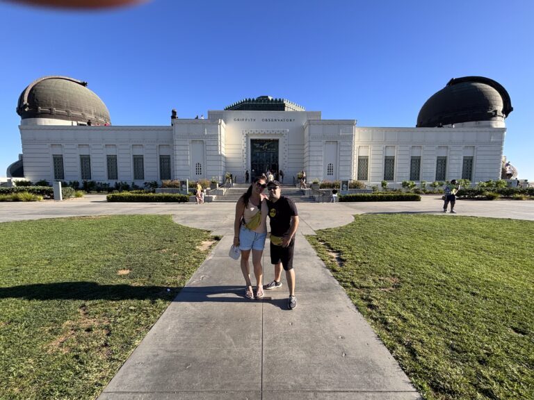 Alessia e Michael posano davanti al Griffith Observatory bianco con cupole di rame a Los Angeles