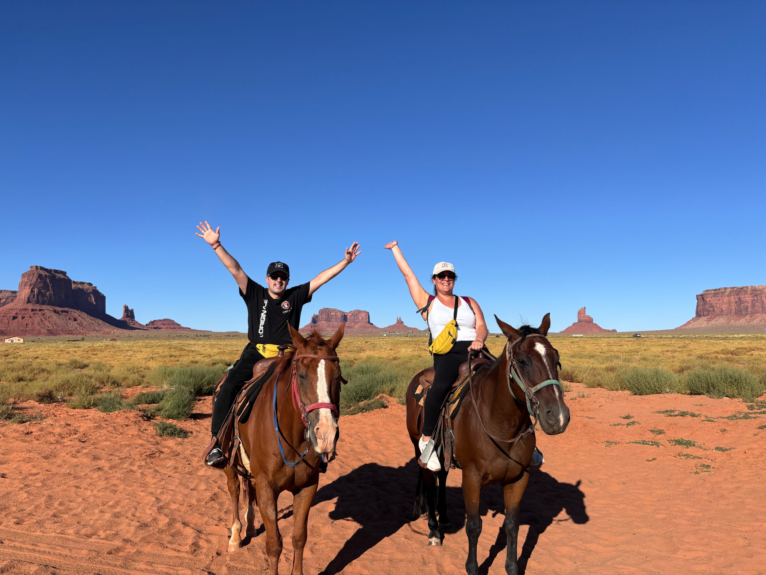 Alessia e Michael a cavallo in Monument Valley Navajo Tribal Park con buttes in arenaria rossa sullo sfondo