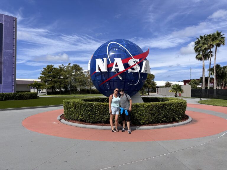 Alessia e Michael di Red Lace posano davanti al globo terrestre con il logo NASA nella piazza Kennedy Space Center in Florida