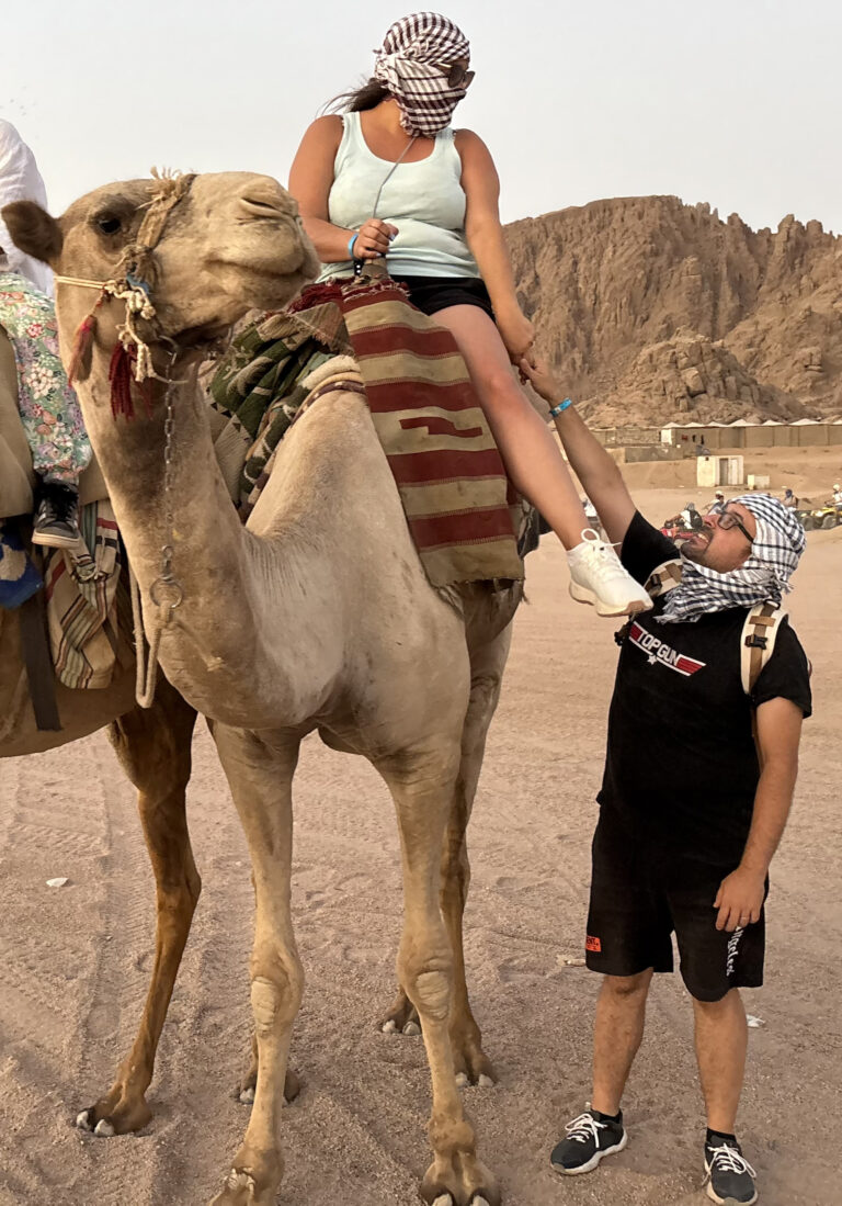Michael Triverio e Alessia durante un giro in cammello nel deserto del Sinai a Sharm El Sheikh: lei in sella al cammello con kefiah, lui che la aiuta a prepararsi